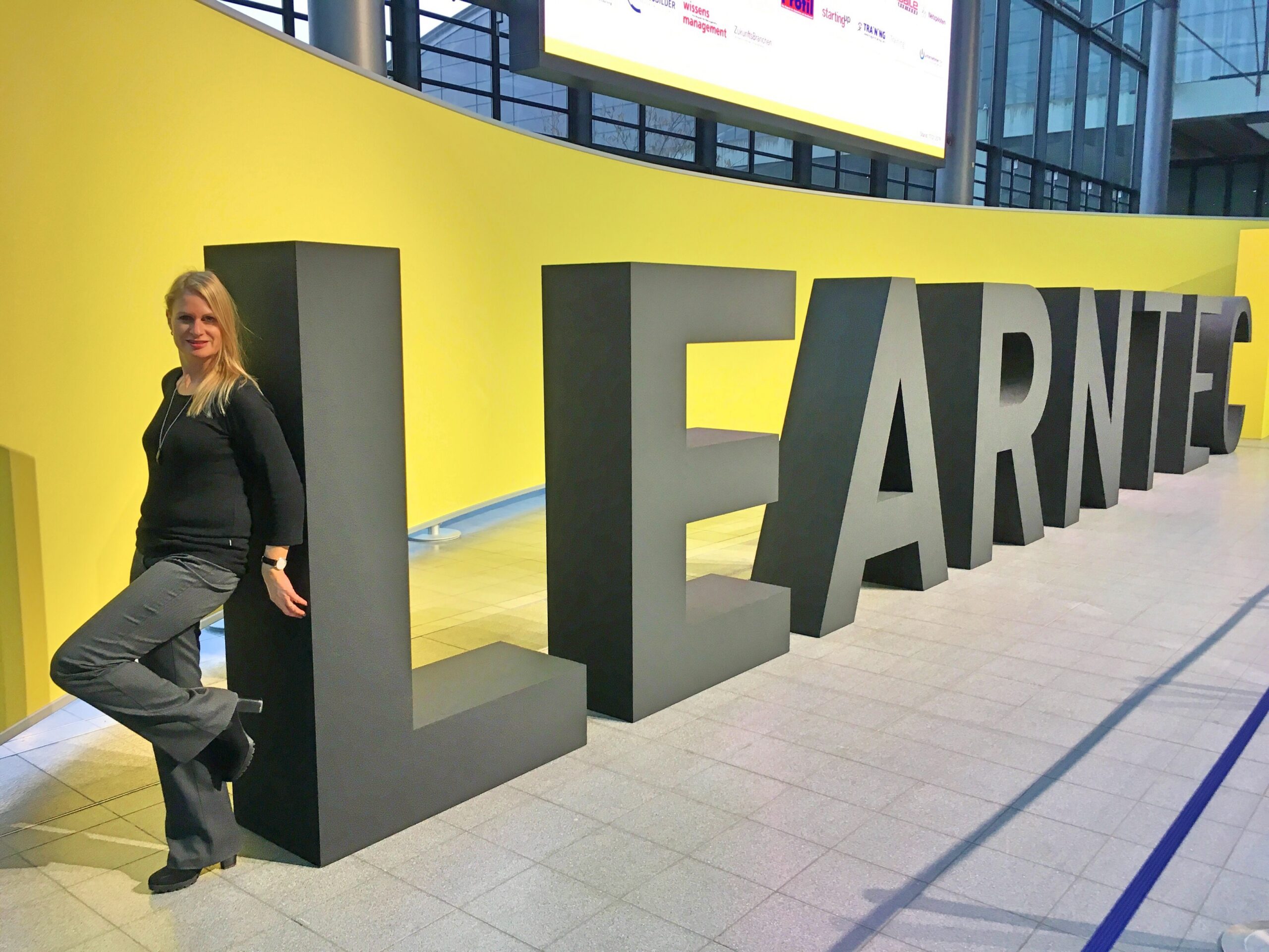 Martina Maier lehnt an großem LEARNTEC-Schriftzug in der Messehalle Karlsruhe
